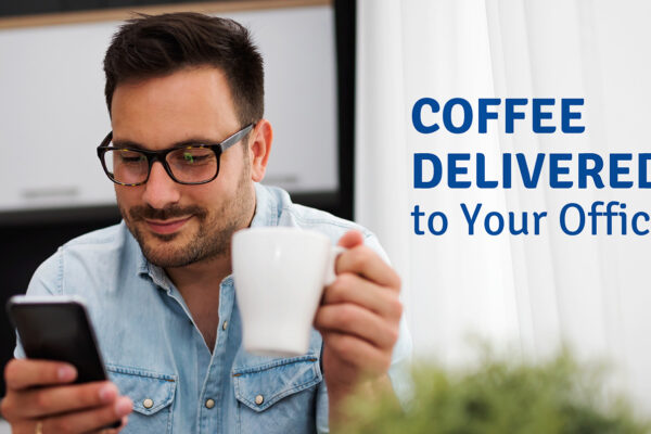 A man with a coffee cup in one hand and a phone in the other